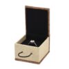 Open burlap-covered ring box with a dark interior holding a ring
