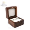 Open walnut ring box with a white cushion holding two rings