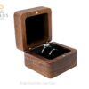 Open walnut ring box with a black cushion holding two rings