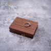 Closed rectangular walnut ring box with a ring resting on the lid