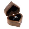 Open heart-shaped wooden ring box with a black cushion and one ring