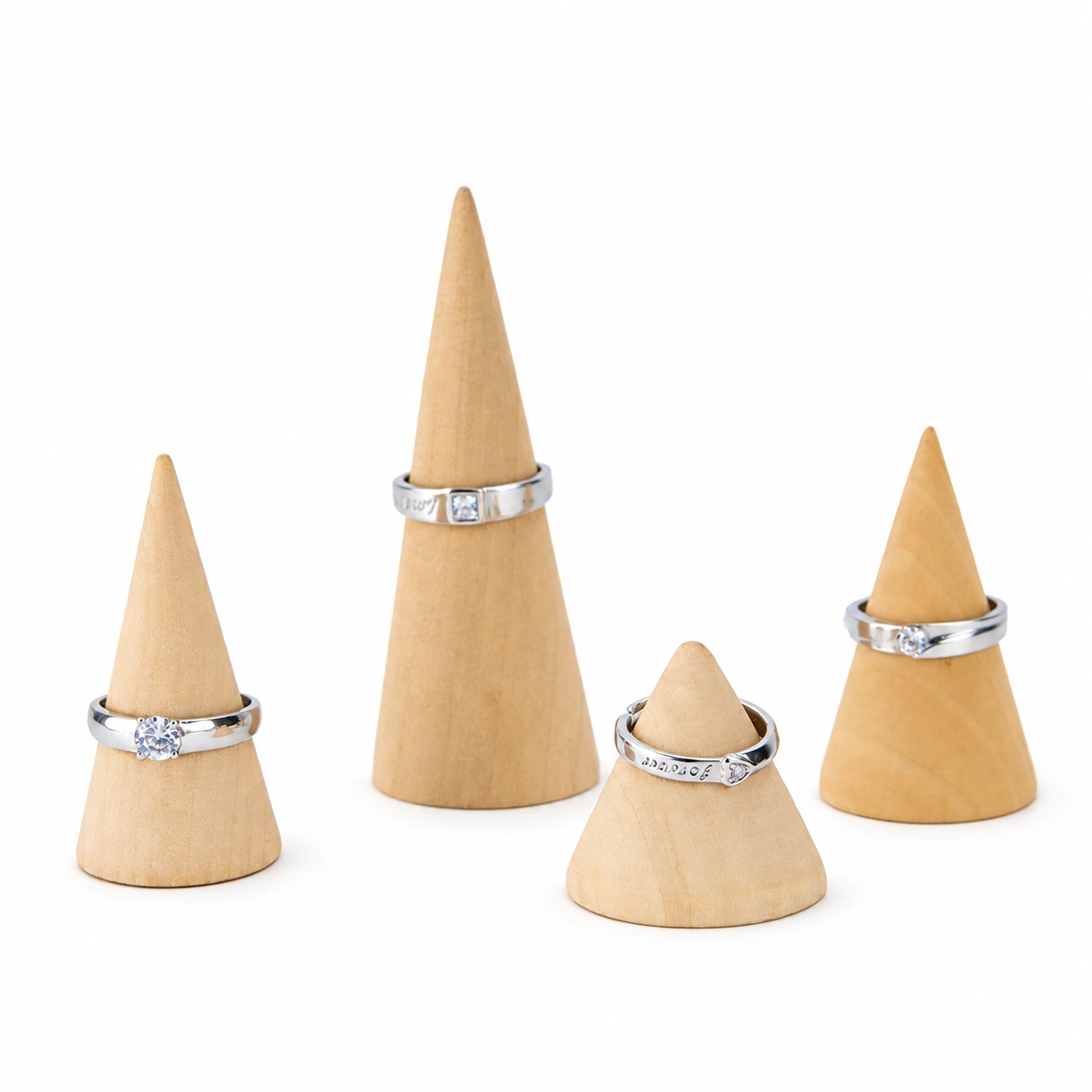 Four natural wooden cone ring stands displaying rings on a white background